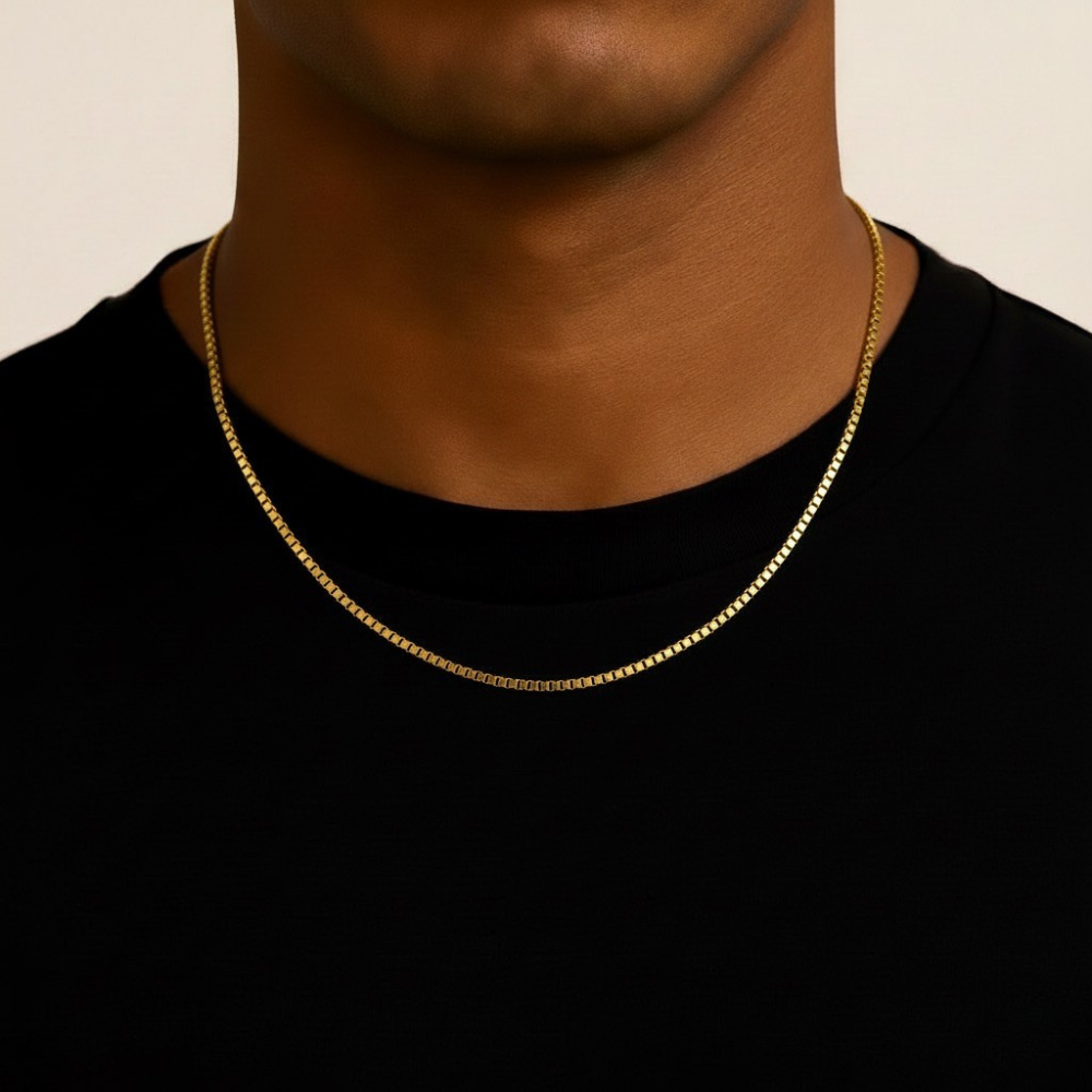Gold chain necklace on a person wearing a black shirt against a beige background
