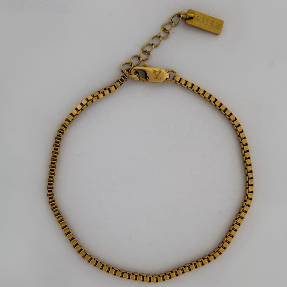 Gold bracelet with a visible brand logo on a white background