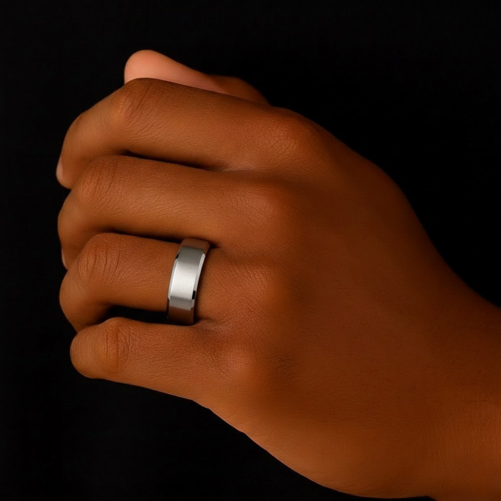 Hand wearing a stainless steel ring on a black background