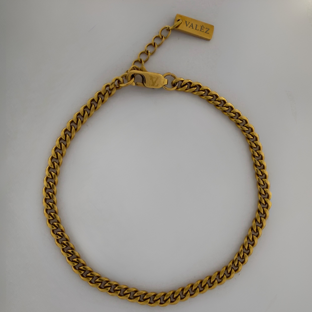 Gold cuban link bracelet with 'VALEZ' clasp on a light gray background