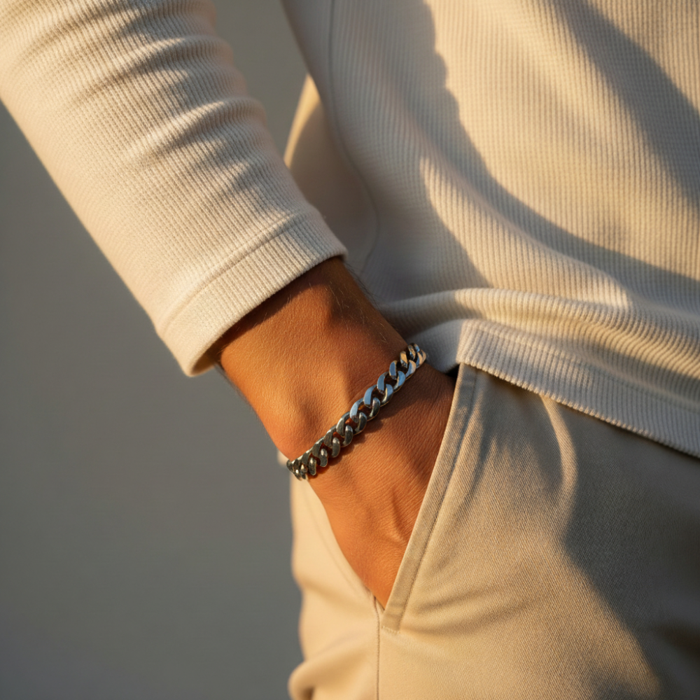 Close-up of a person wearing the silver cuban chain bracelet on a neutral background