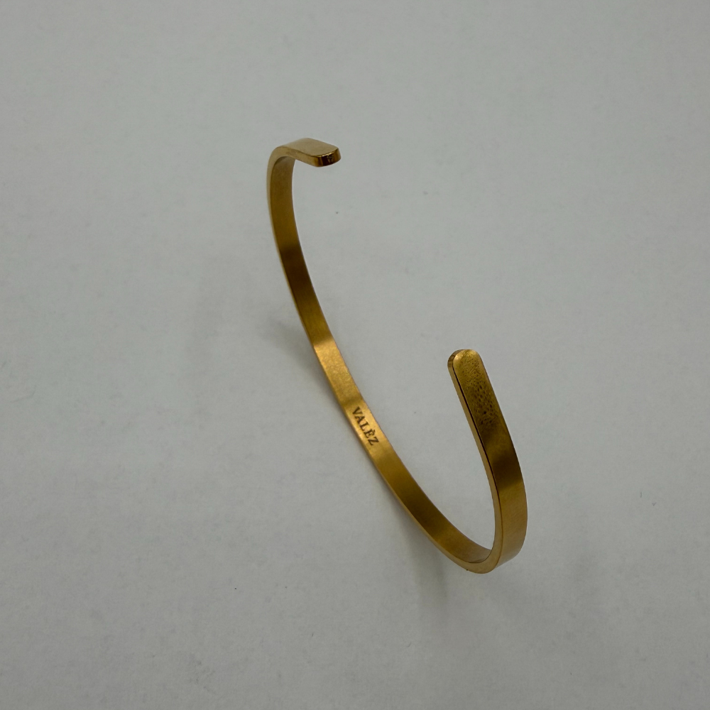 Gold cuff bracelet on a light gray background