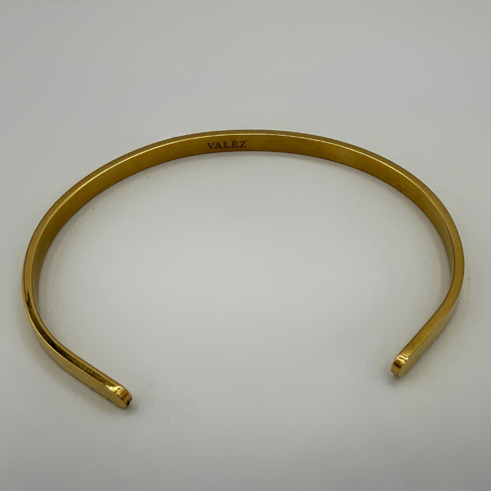 Gold cuff bracelet on a light gray background