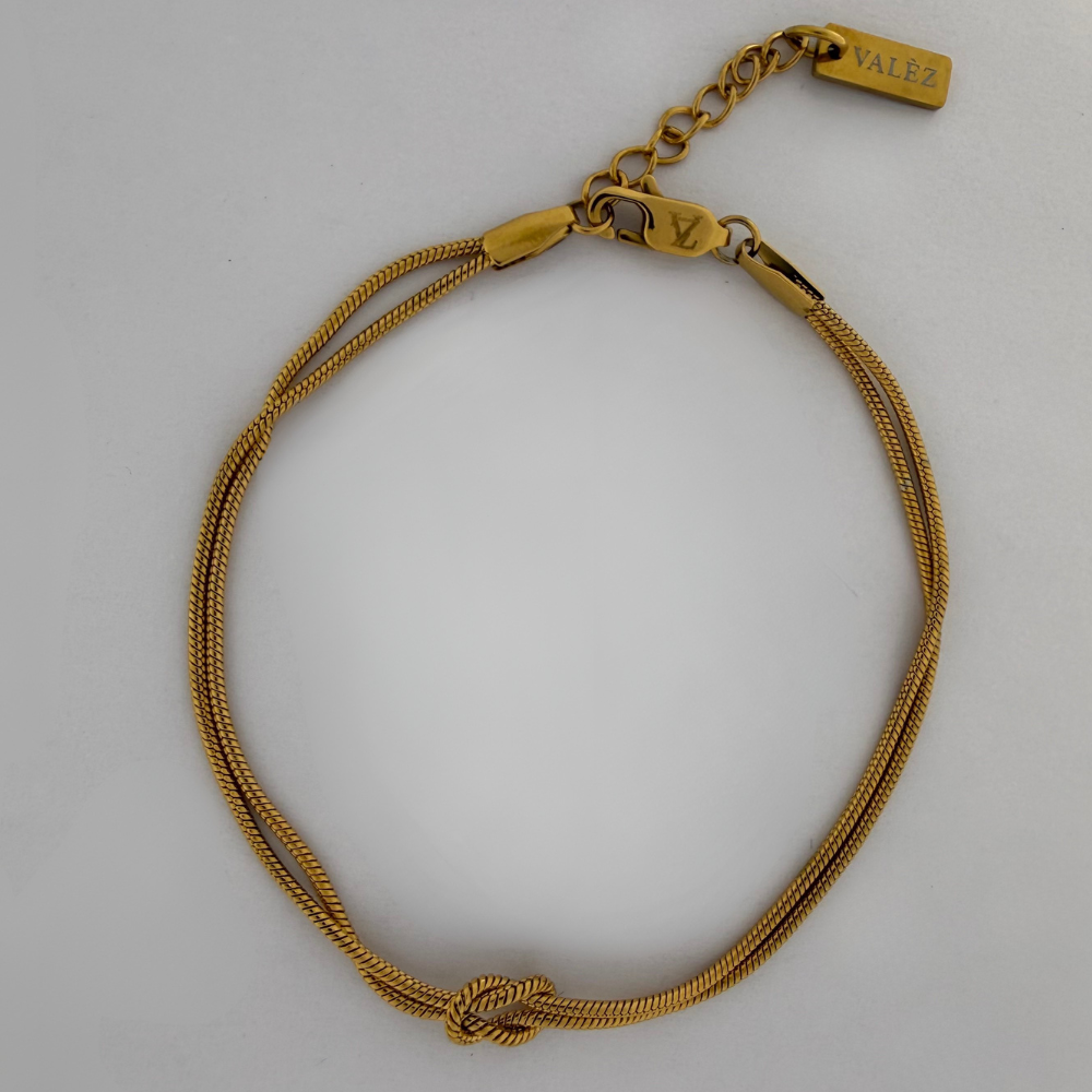 Gold Infinity bracelet with a knot design on a light gray background