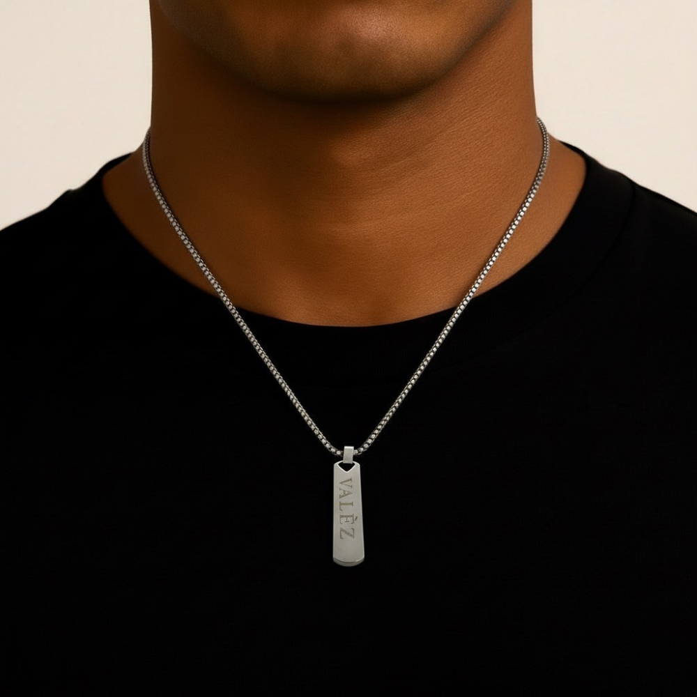 Person wearing a stainless steel necklace with a pendant on a beige background