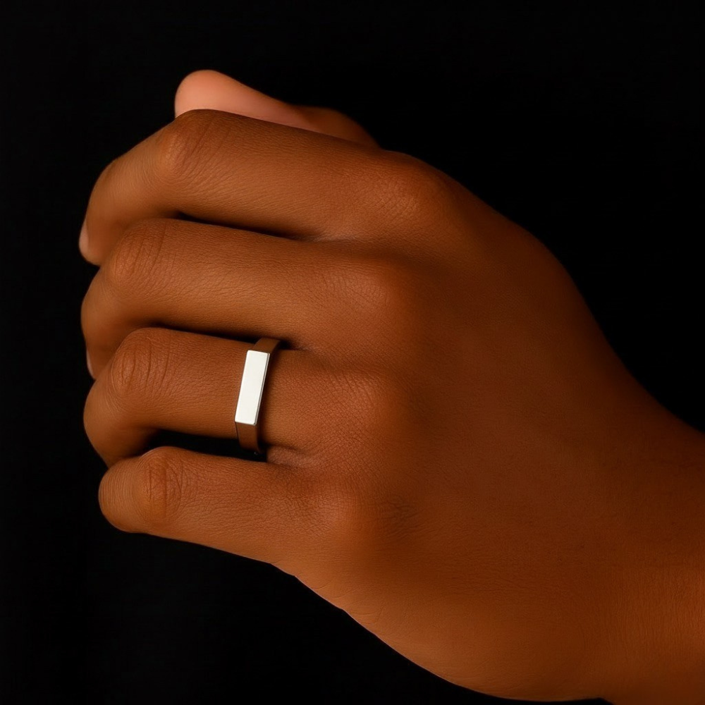 Hand wearing a stainless steel ring on a black background