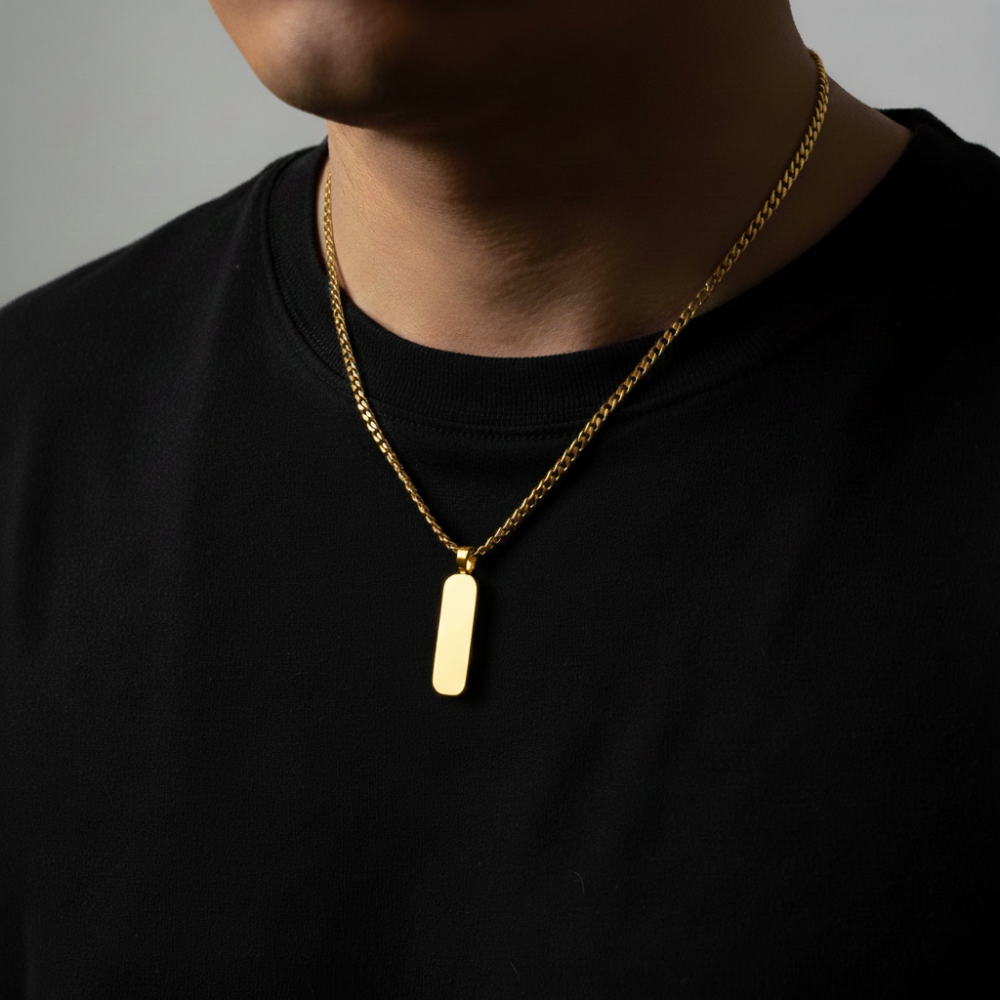 Gold necklace with a pendant on a black shirt against a gray background