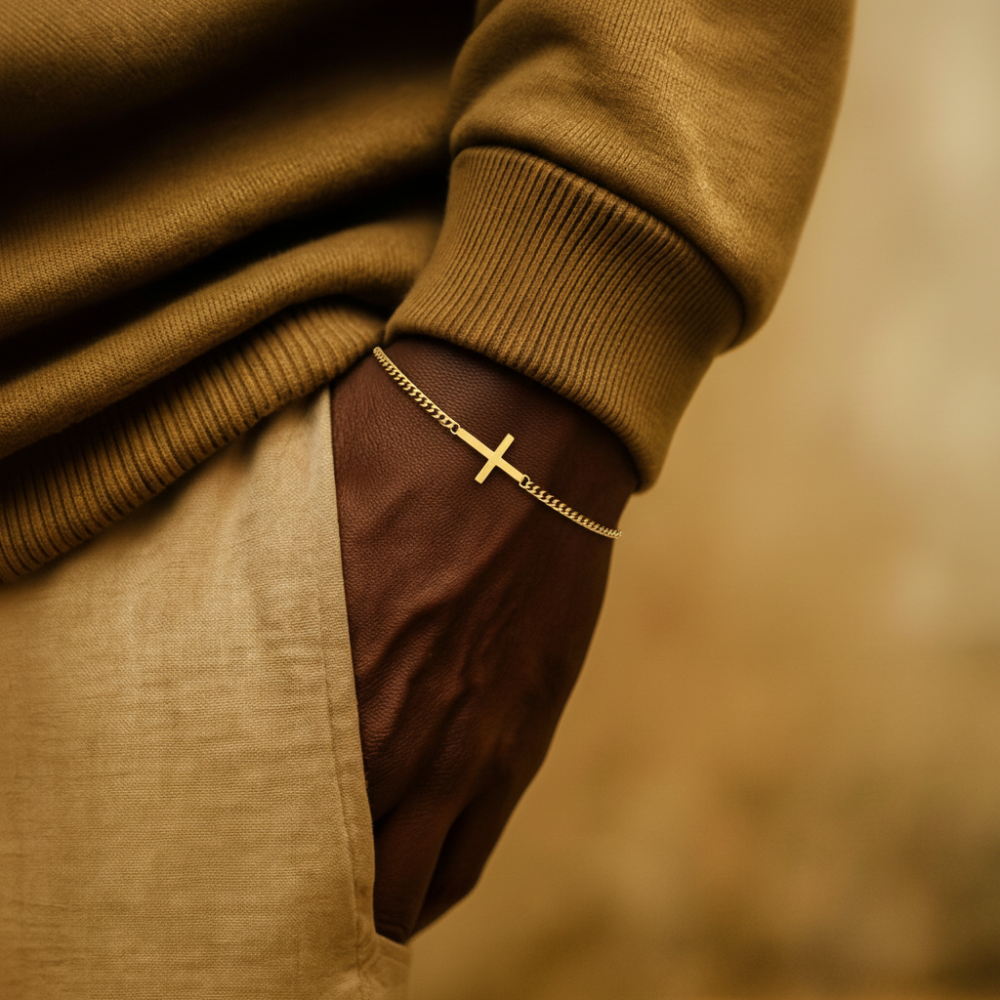 Close-up of a person wearing a brown sweater with a gold cross bracelet on a blurred background