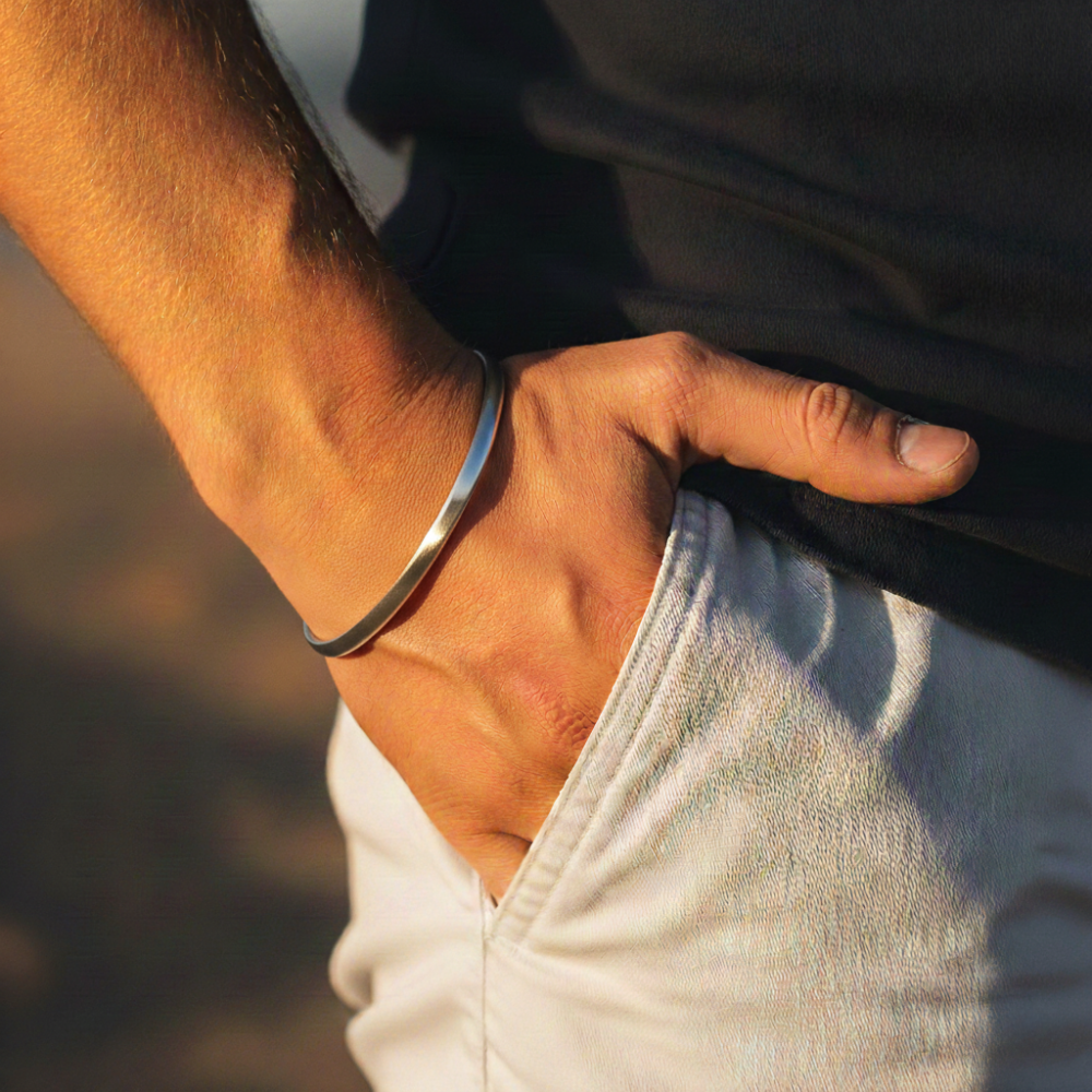 Hand wearing a silver cuff bracelet with a blurred background