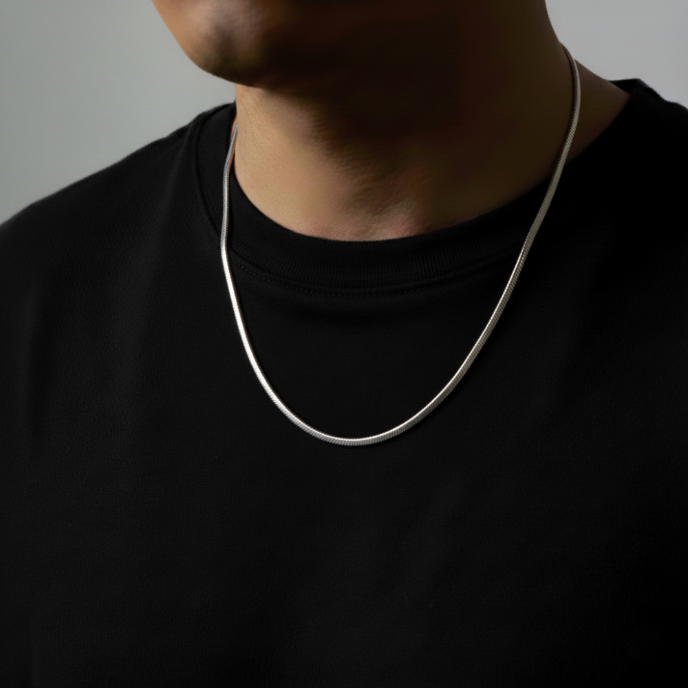 Person wearing a silver necklace against a neutral background