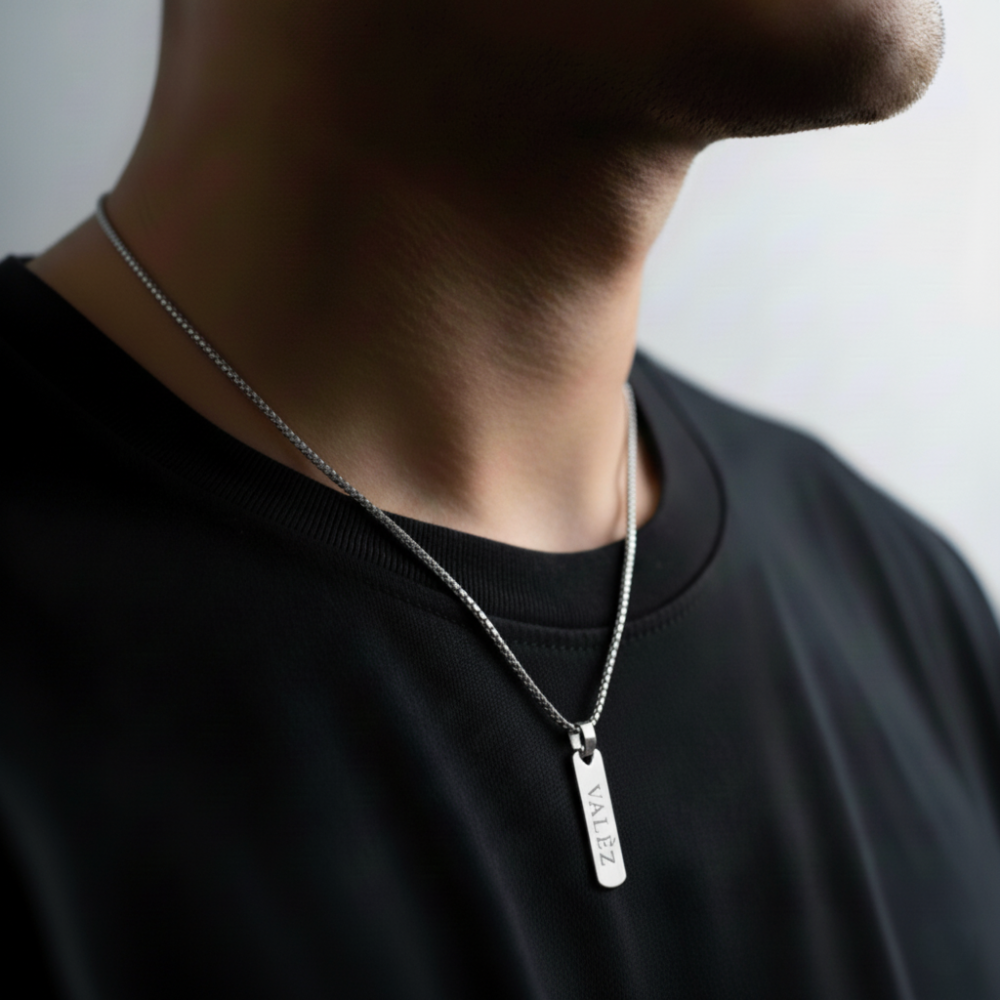 Person wearing a silver necklace with a valèz pendant against a neutral background