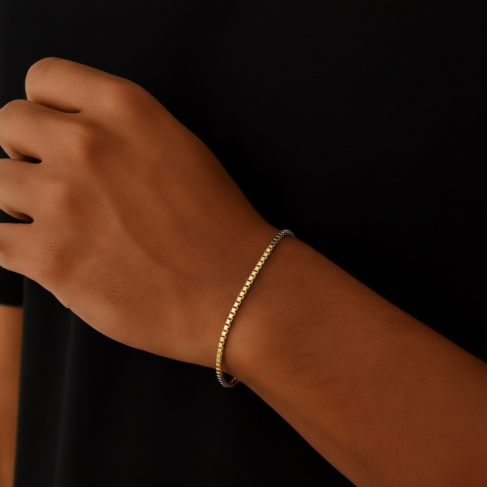 Gold bracelet on a wrist against a black background