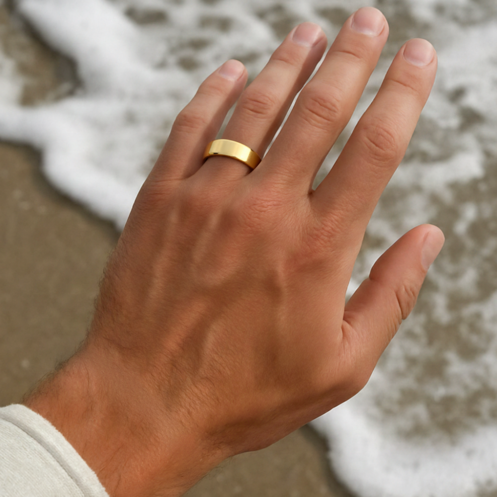 Hand wearing a gold ring with a beach background