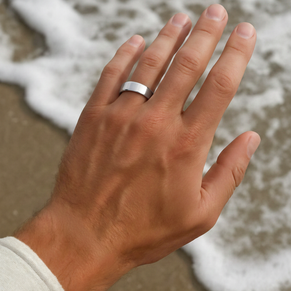 Hand with a silver ring on a beach
