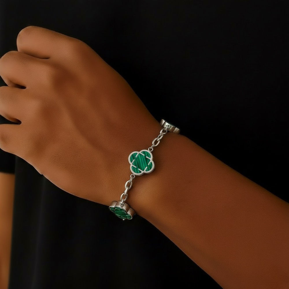 stainless steel Bracelet with green clover charms on a wrist against a black background