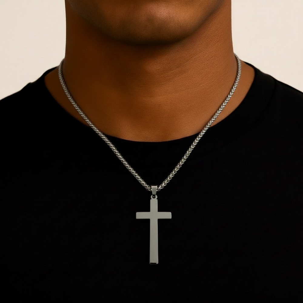 Stainless steel cross necklace on a person wearing a black shirt against a beige background