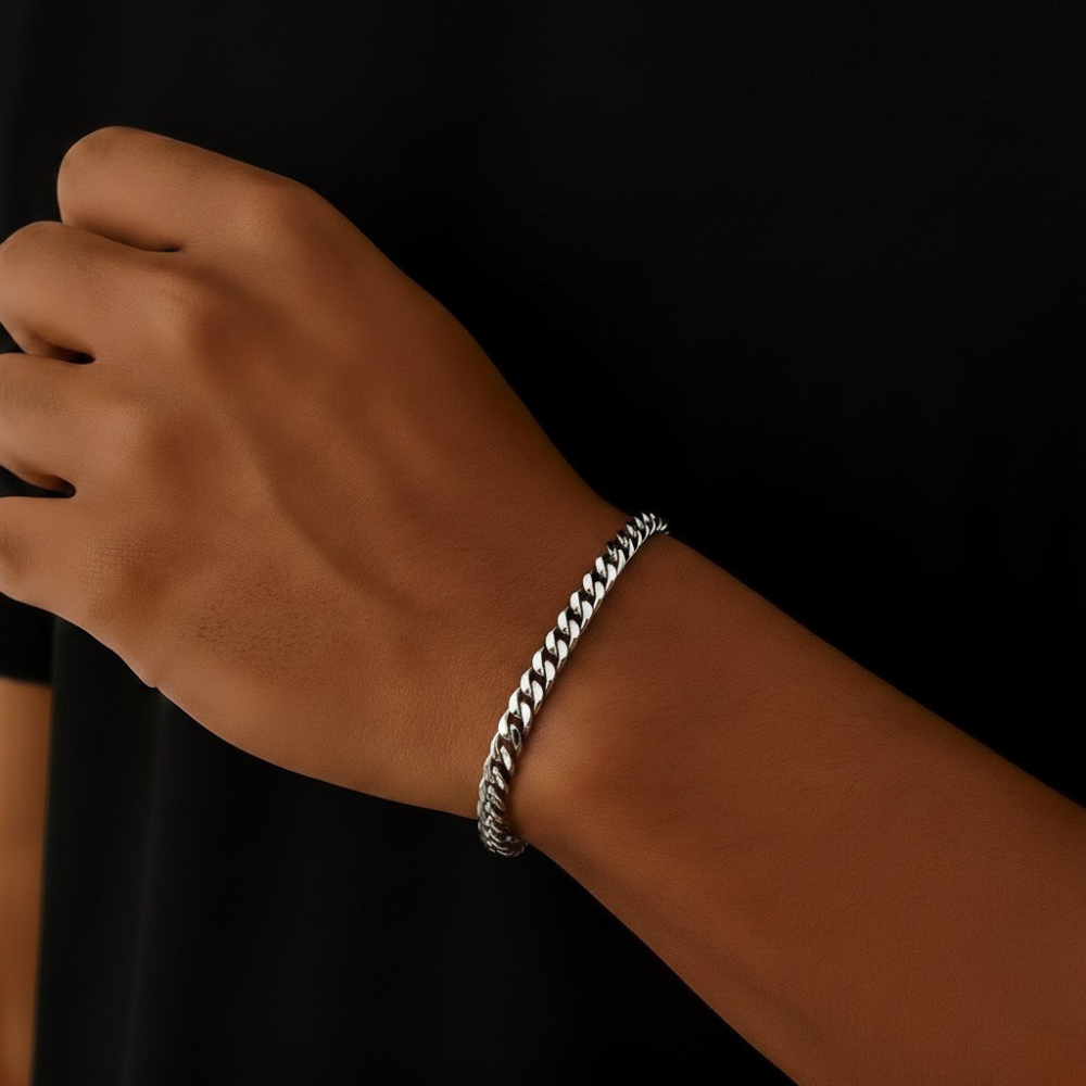 stainless steel Cuban Link bracelet on a wrist against a black background