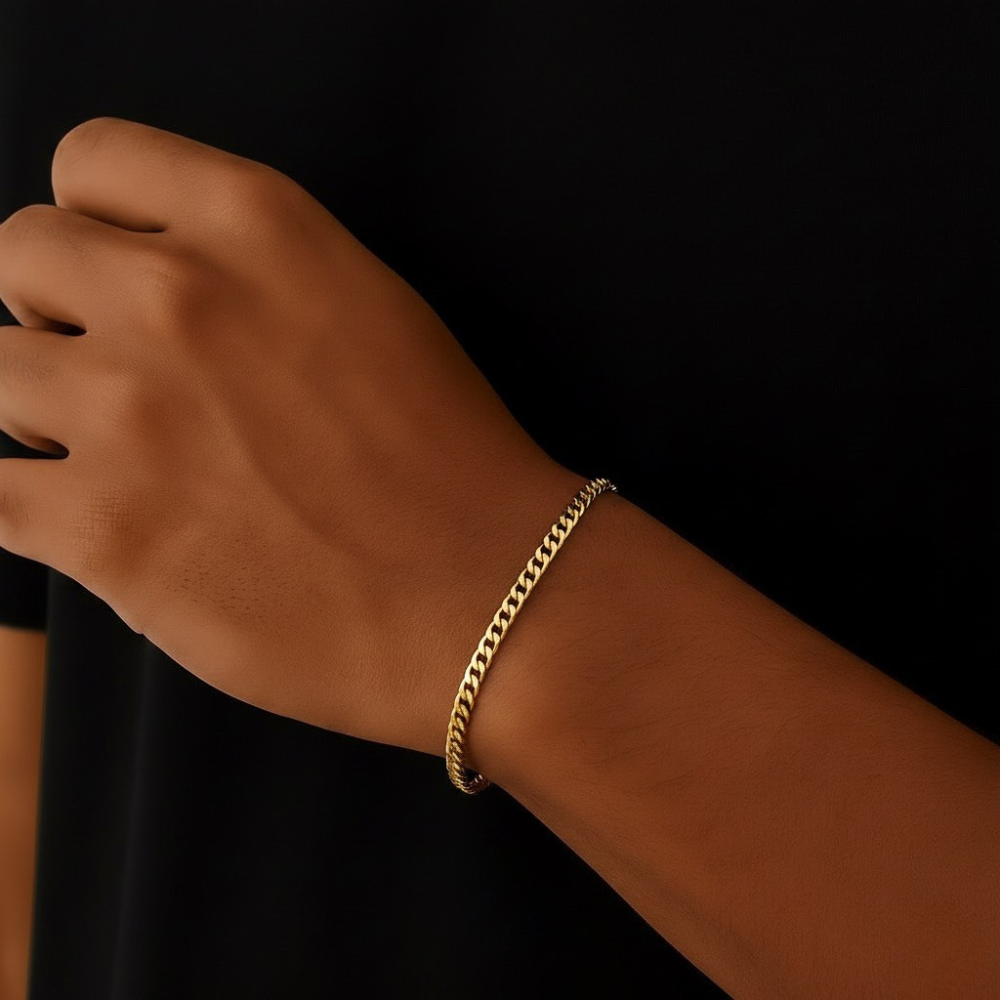 Gold cuban link bracelet on a wrist against a black background