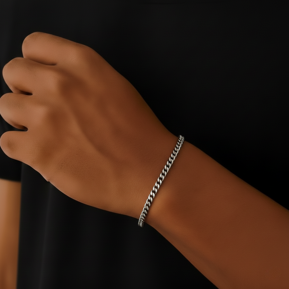 Hand wearing a silver cuban bracelet on a black background