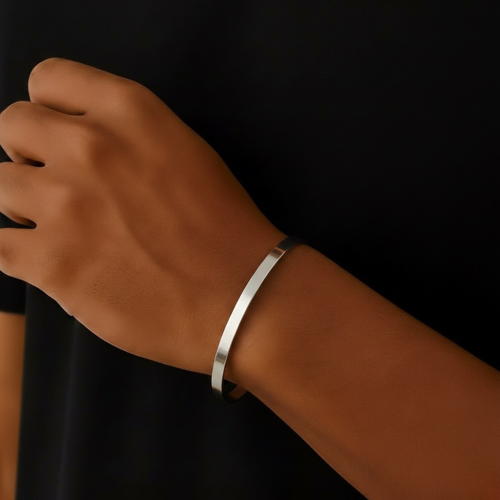Stainless steel cuff bracelet on a wrist against a black background