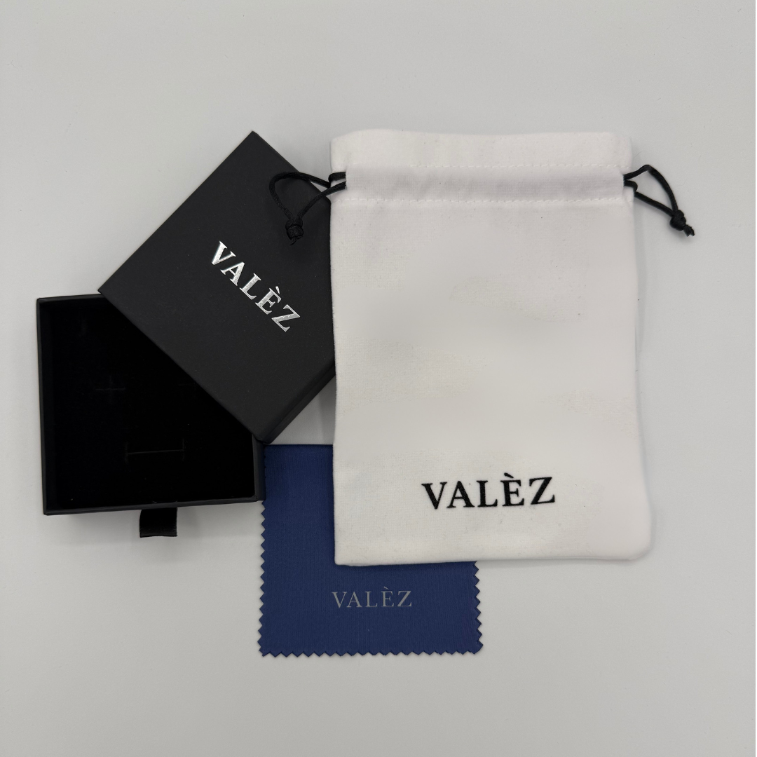 Valèz branded packaging including a black box, white pouch, and blue cleaning cloth on a light gray background.
