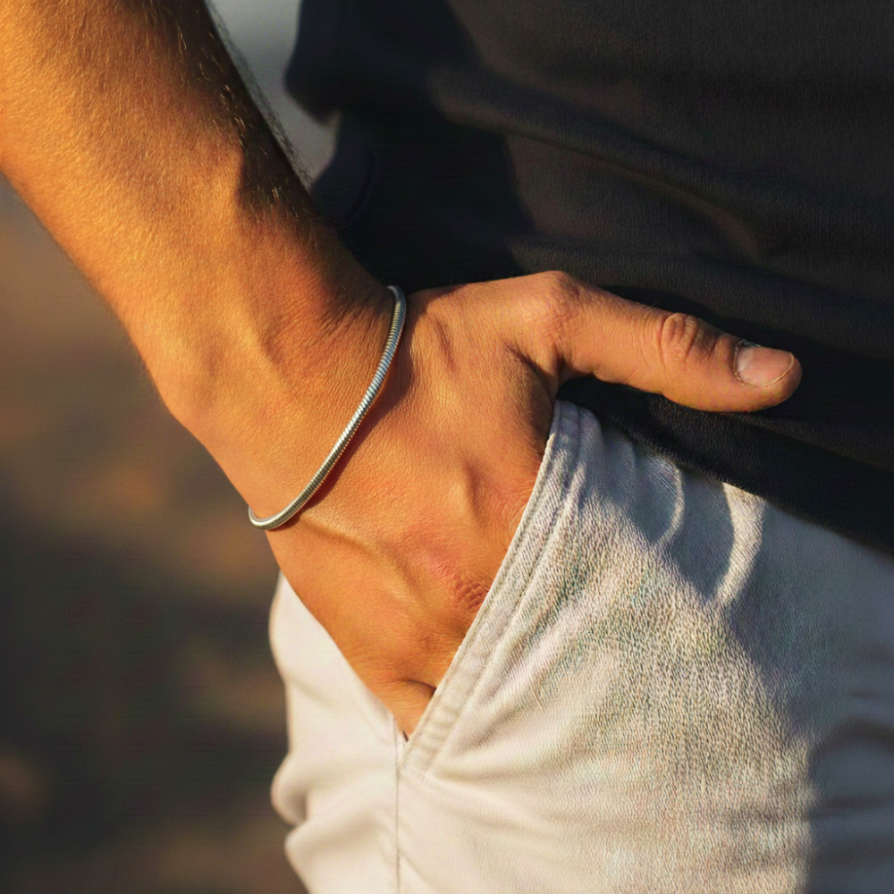 Close-up of a person's arm with a silver square bracelet on a blurred background