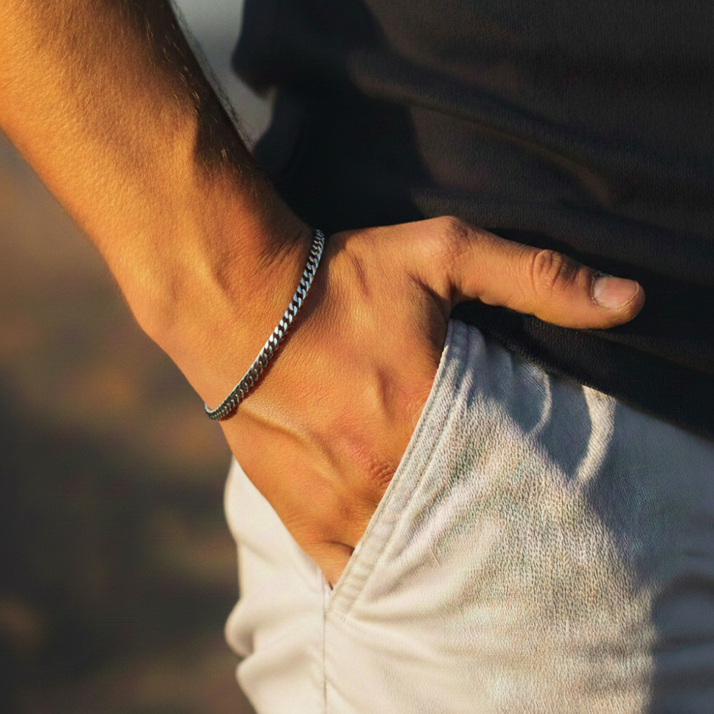 Close-up of a person's arm with a cuban bracelet, against a blurred background