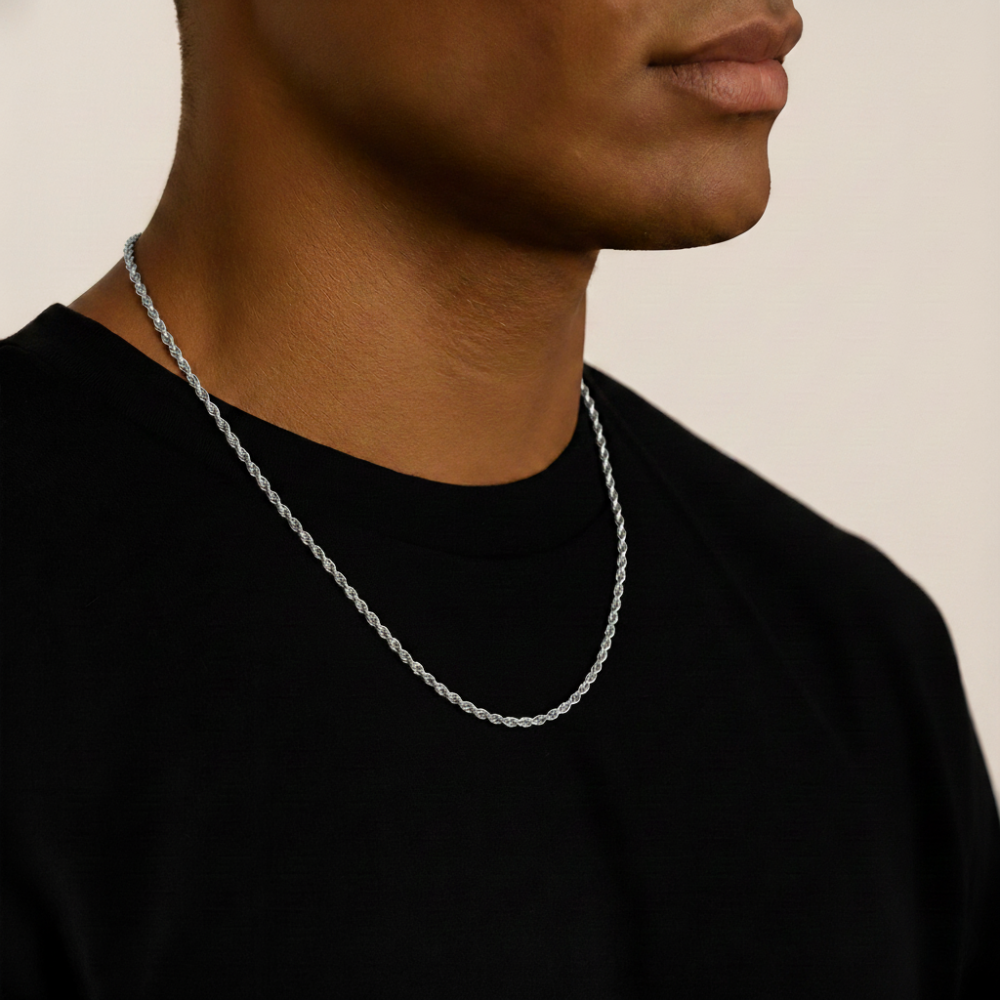 Person wearing a silver rope chain necklace against a neutral background
